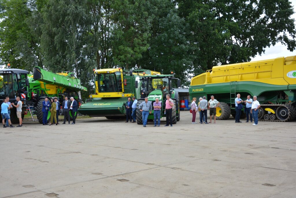 uczestnicy spotkania na tle maszyn rolniczych