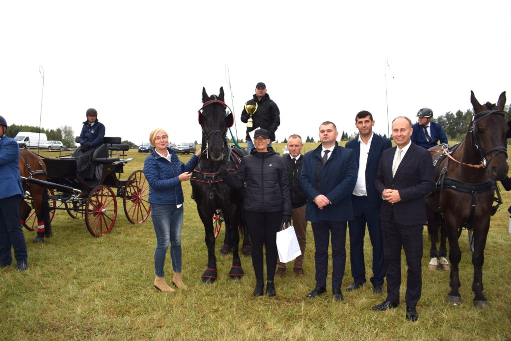 Zdjęcie grupowe oficjeli ze laureatem zawodów w powożeniu zaprzęgami konnymi.