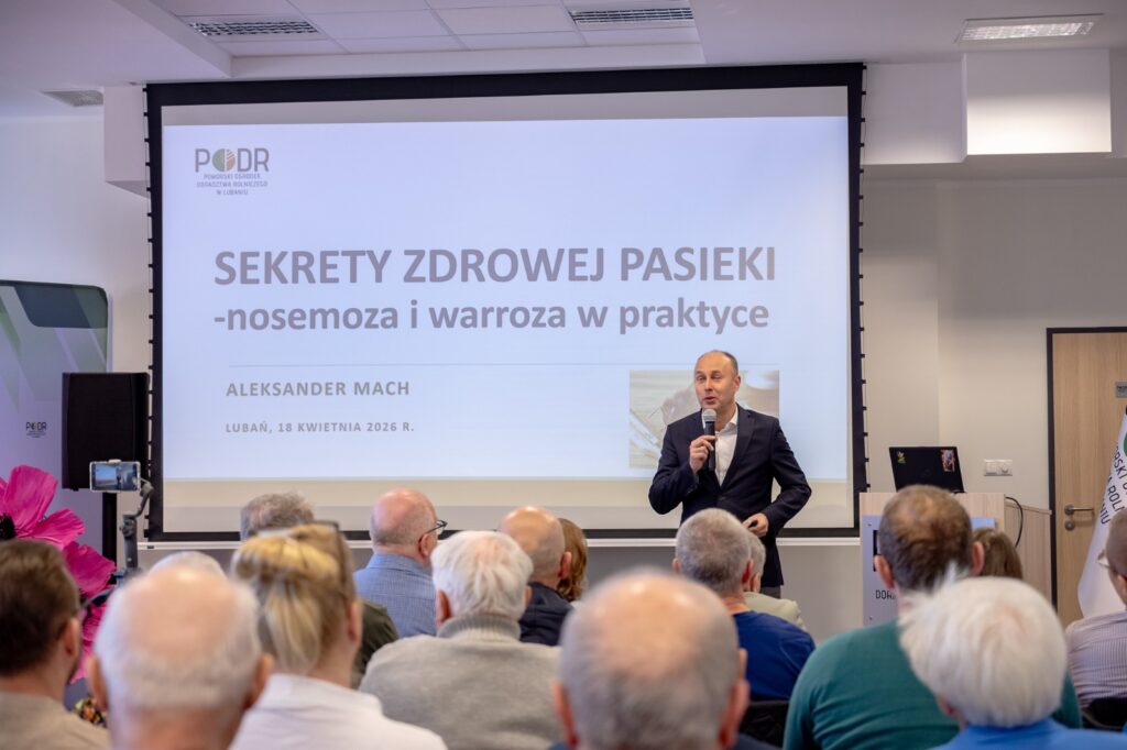 Sala konferencyjna podczas prezentacji – uczestnicy, przemawiający dyrektor Aleksander Mach i slajd na ekranie