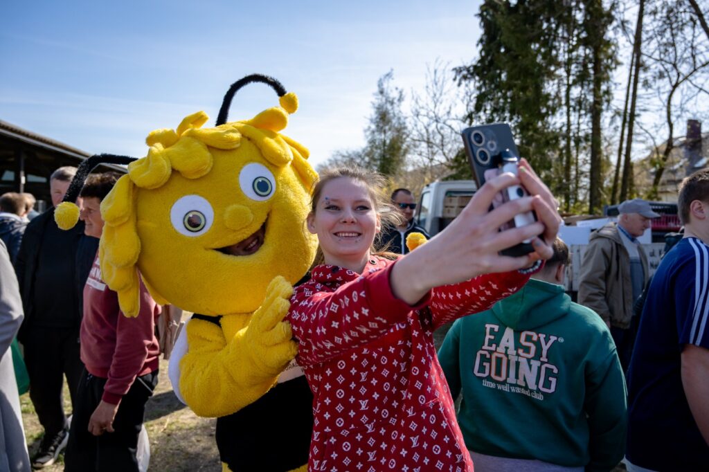 Uczestnicy robiący zdjęcie z maskotką pszczoły podczas wydarzenia