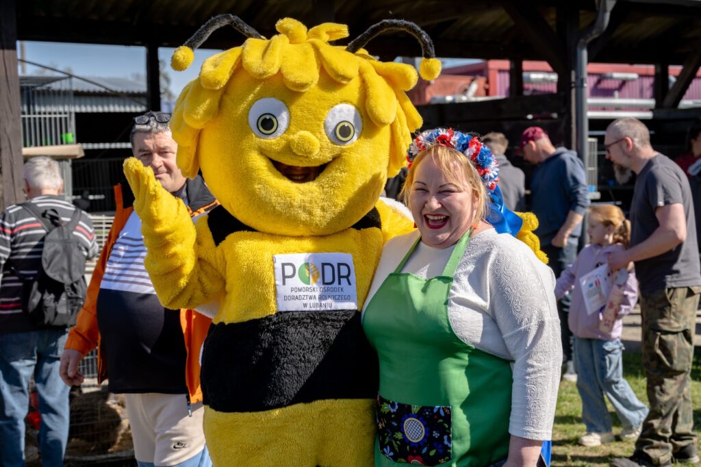 Maskotka pszczoły pozująca do zdjęcia z odwiedzającą targi