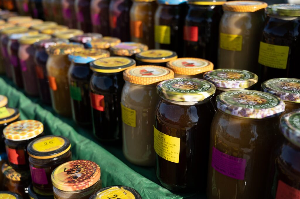 Słoiki z miodem i produktami pszczelimi prezentowane na stoisku