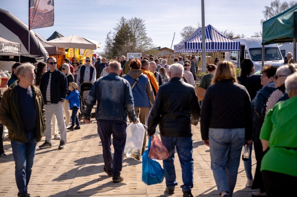 Odwiedzający spacerujący alejką między stoiskami targowymi