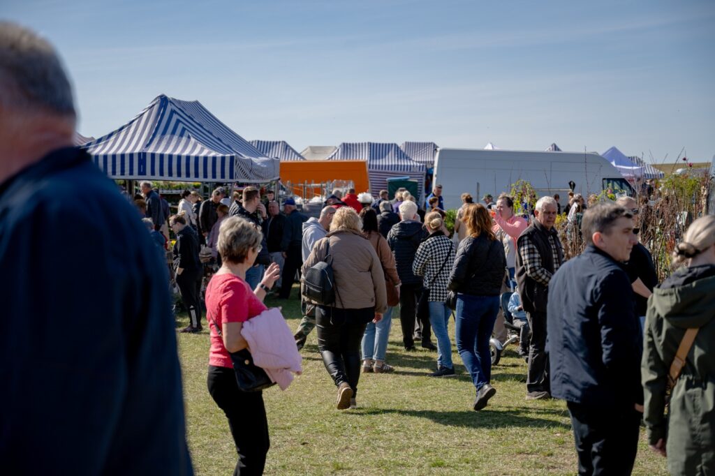 Odwiedzający spacerujący między stoiskami na terenie targów